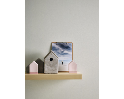 Dekorativa hus av betong och ett fotografi på en trähylla.