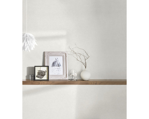 Vardagsrum med tapet, hylla och dekorativa element som fotoramar och vas