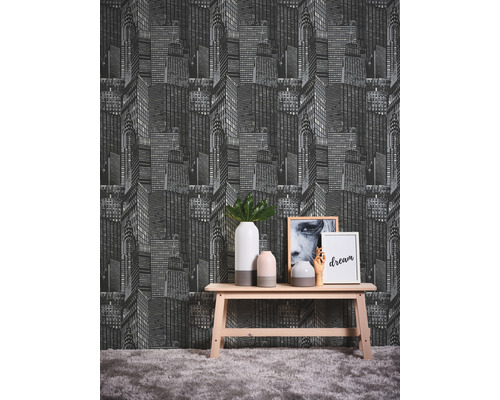 Rum med en tapet med ett skyskrapamönster bakom ett träbord