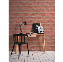 Skrivbord med stol, lampa och väggmålningar framför en tegelvägg