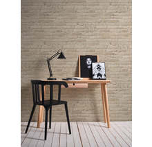 Skrivbord med stol, lampa och dekoration mot en tegelvägg