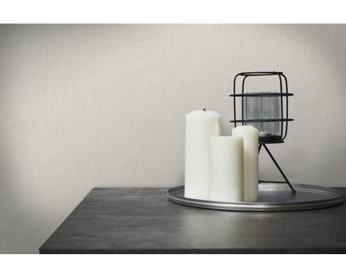 Dekorativ scen med canvastapet, ljus och lykta på ett bord.