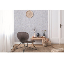 Vardagsrum med mönstrad tapet, rottingfåtölj och trägolv