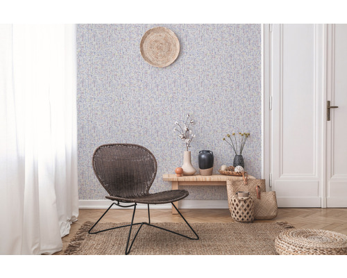 Vardagsrum med mönstrad tapet, rottingfåtölj och trägolv