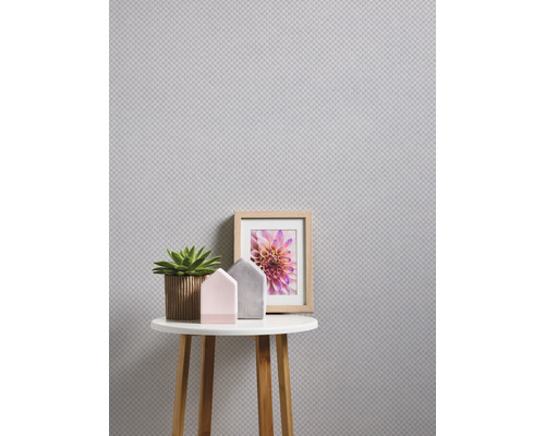 Närbild av ett litet bord med dekoration mot en strukturerad vägg