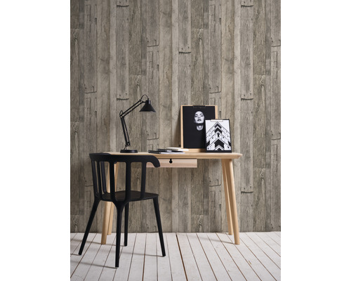 Arbetsrum med skrivbord, stol, skrivbordslampa och dekoration framför en tapet i trälook