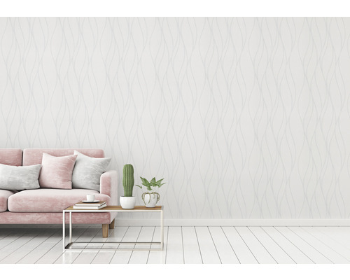 Vardagsrum med rosa soffa, bord och mönstrad tapet för en ljus och vänlig atmosfär.