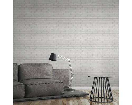 Vardagsrum med soffa, golvlampa och sidobord framför en vägg med tegelstapeter.