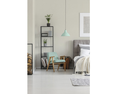 Ljust sovrum med fåtölj, säng och hylla