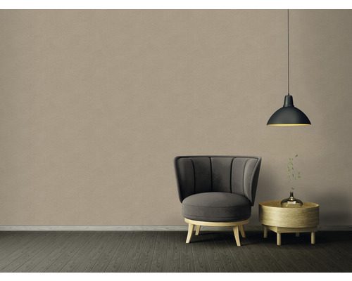 Inredning med fåtölj, sidobord och hänglampa framför en beige vägg