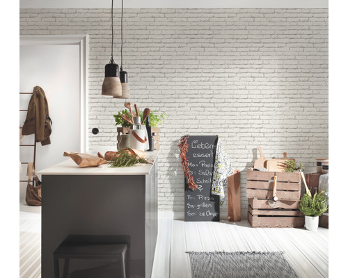 Ljust kök med köksö, griffeltavla och träaccenter mot en vit tegelvägg