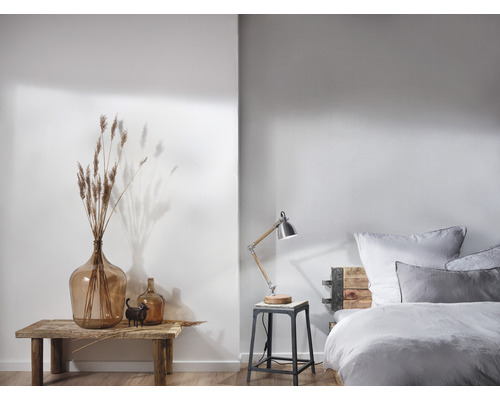 Ljust sovrum med säng, sänglampa och dekoration på ett träbord