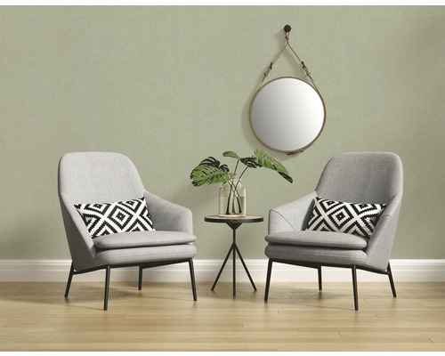 Ljus interiör med två grå fåtöljer, ett sidobord och en rund spegel på väggen