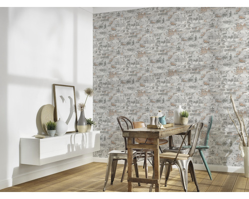 Matsal med väggtapet i tegelstensdesign, bord och stolar.