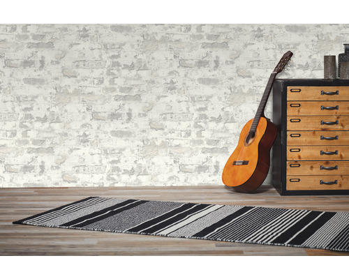 Dekorativt rum med gitarr, matta och byrå framför en tapet i murverksdesign.