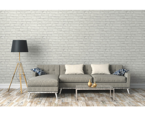 Vardagsrum med grå soffa, golvlampa och soffbord framför en tegelvägg