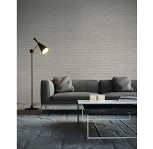 Vardagsrum med grå soffa, soffbord och golvlampa framför en tegelvägg