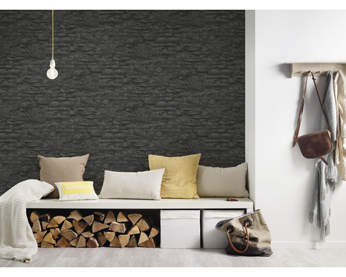 Vardagsrum med en väggbeklädnad i stenimitation, en sittmöbel, kuddar och ved.