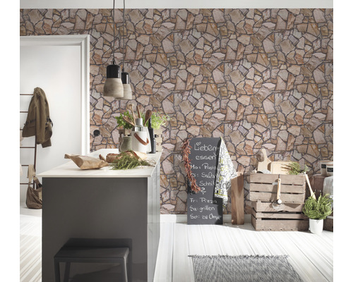 Ljust kök med tapet i stenimitation, köksö och dekorativa element.