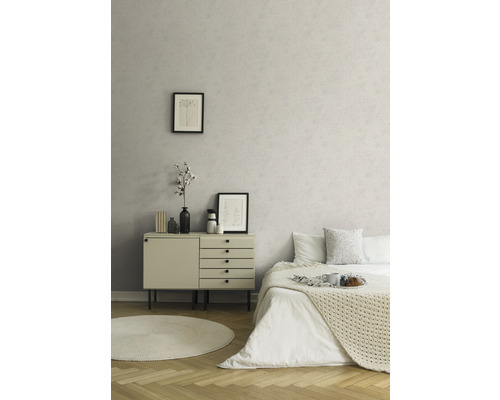Ljust rum med beige byrå och säng mot en mönstrad vägg