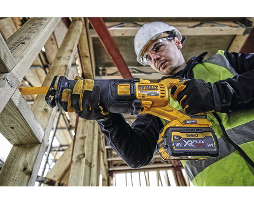 En man med skyddsglasögon och hjälm arbetar med en DeWalt sladdlös tigersåg på en träram.
