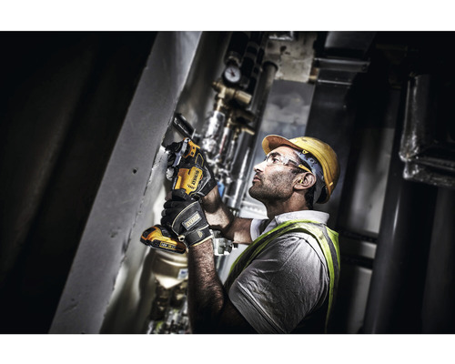 En hantverkare i skyddskläder använder ett oscillerande elverktyg från DeWalt på en vägg.