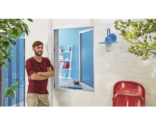 Man står framför en öppen dörr med insektsskydd och utsikt över en terrass med lampa och stol