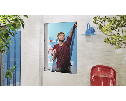 Man fäster ett insektsnät på ett fönster utomhus.