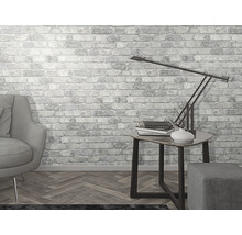 Ljust rum med fåtölj, bordslampa och tapet med tegelmönster