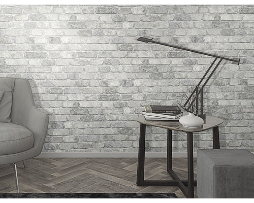 Ljust rum med fåtölj, bordslampa och tapet med tegelmönster