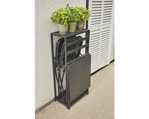 Fällbart bord och fällbara stolar i en hylla, plus växter