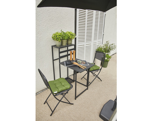 Trädgårdsscen med bord, stolar, växter och hylla framför en vägg