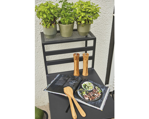 Köksbord med örter, kokbok, matskedar och kryddkvarnar