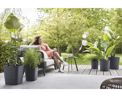 Kvinna kopplar av i trädgården med växter i planteringskärl på terrassen