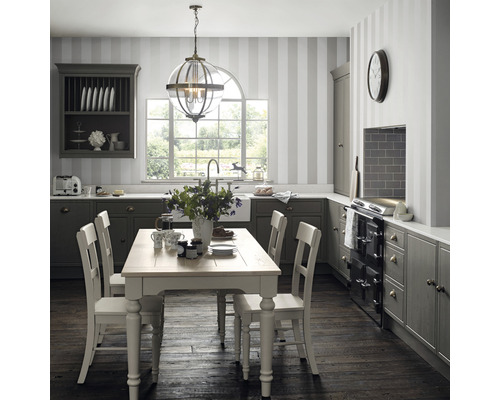 Klassiskt kök med matbord, stolar, hängande lampa och köksskåp.