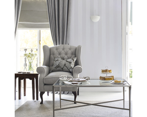 Vardagsrum med fåtölj, soffbord, gardiner och dekoration