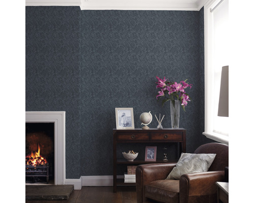 Vardagsrum med mönstrad tapet, öppen spis och brun läderfåtölj