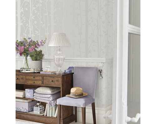 Dekorativt rum med byrå, lampa och tapet med trämotiv