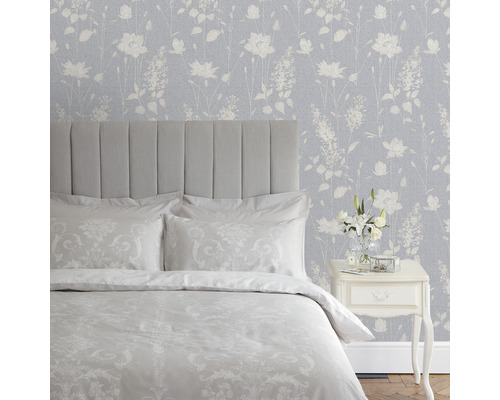 Sovrum med säng, nattduksbord och blommig tapet