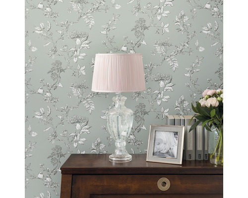 Dekorativt rum med blomstertapet, sänglampa, böcker och bukett