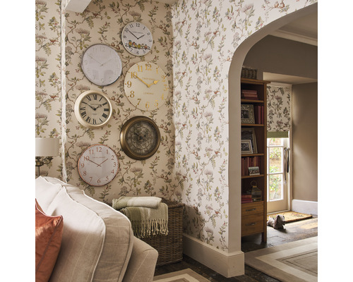 Vardagsrum med blommig tapet och en samling väggklockor i olika designer