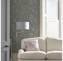 Vardagsrum med soffa, golvlampa och blommönstrad tapet