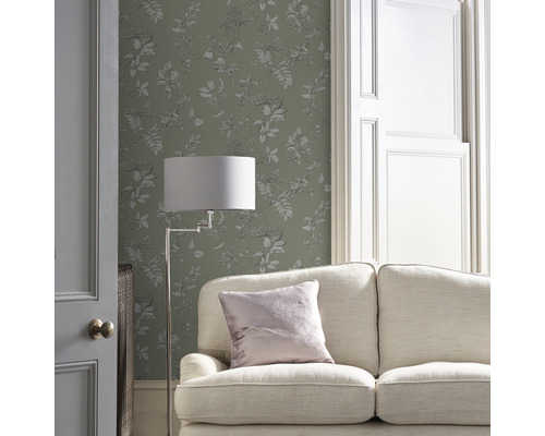 Vardagsrum med soffa, golvlampa och blommönstrad tapet