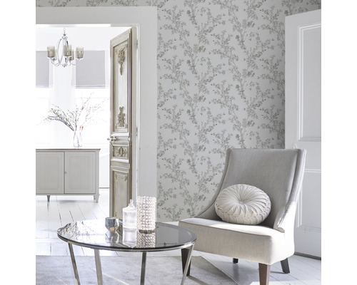 Ljust vardagsrum med blommigt mönstrad tapet, fåtölj, bord och dekoration