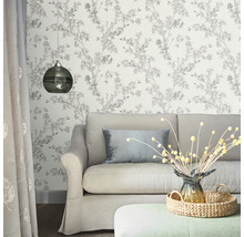 Vardagsrum med soffa, lampa och blommig tapet