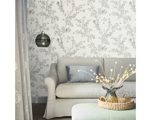 Vardagsrum med soffa, lampa och blommig tapet