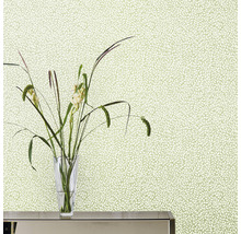 Närbild av en vägg med blommig tapet och en vas med blommor