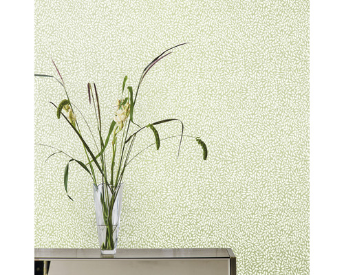 Närbild av en vägg med blommig tapet och en vas med blommor