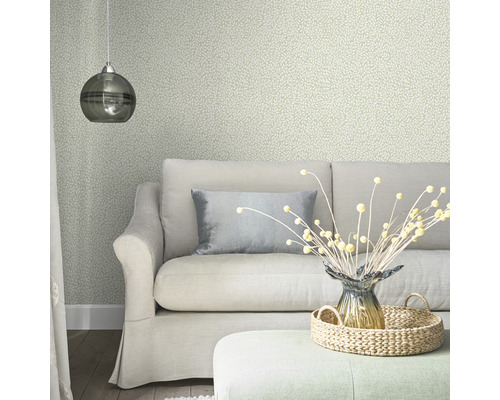 Vardagsrum med soffa, kudde, lampa, dekoration och mönstrad tapet.