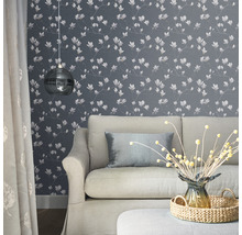 Vardagsrum med soffa, lampa och blommig tapet